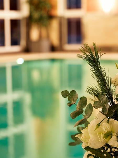 Hotel in Obertauern mit Pool Elegantes Blumenarrangement neben einem Innenpool mit entspannter Atmosphäre